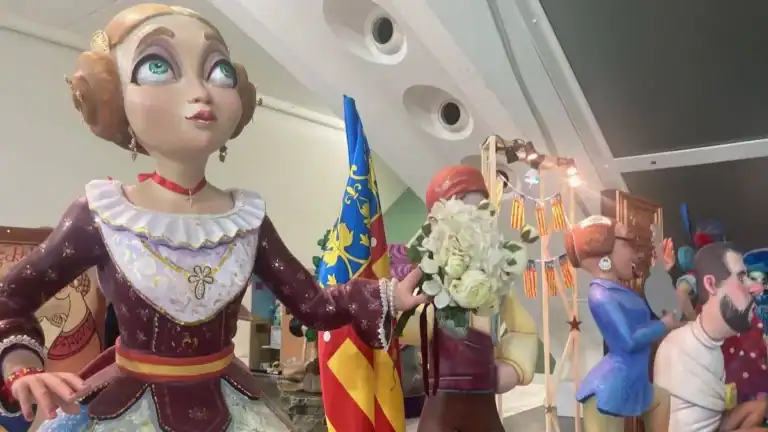 A ninot figure of a blond woman in traditional dress with the Valencian flag