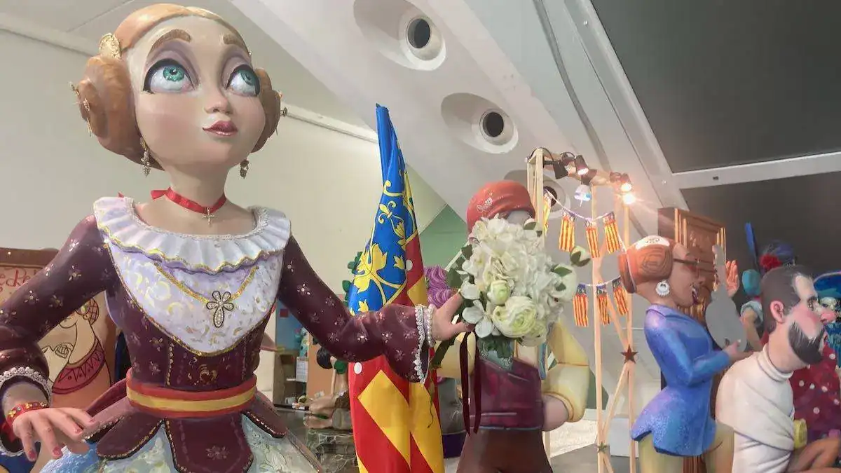 A ninot figure of a blond woman in traditional dress with the Valencian flag