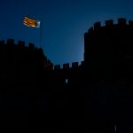 The silhouette of Valencia's iconic Torres de Serranos with a blue, yellow and red Valencian flag flying