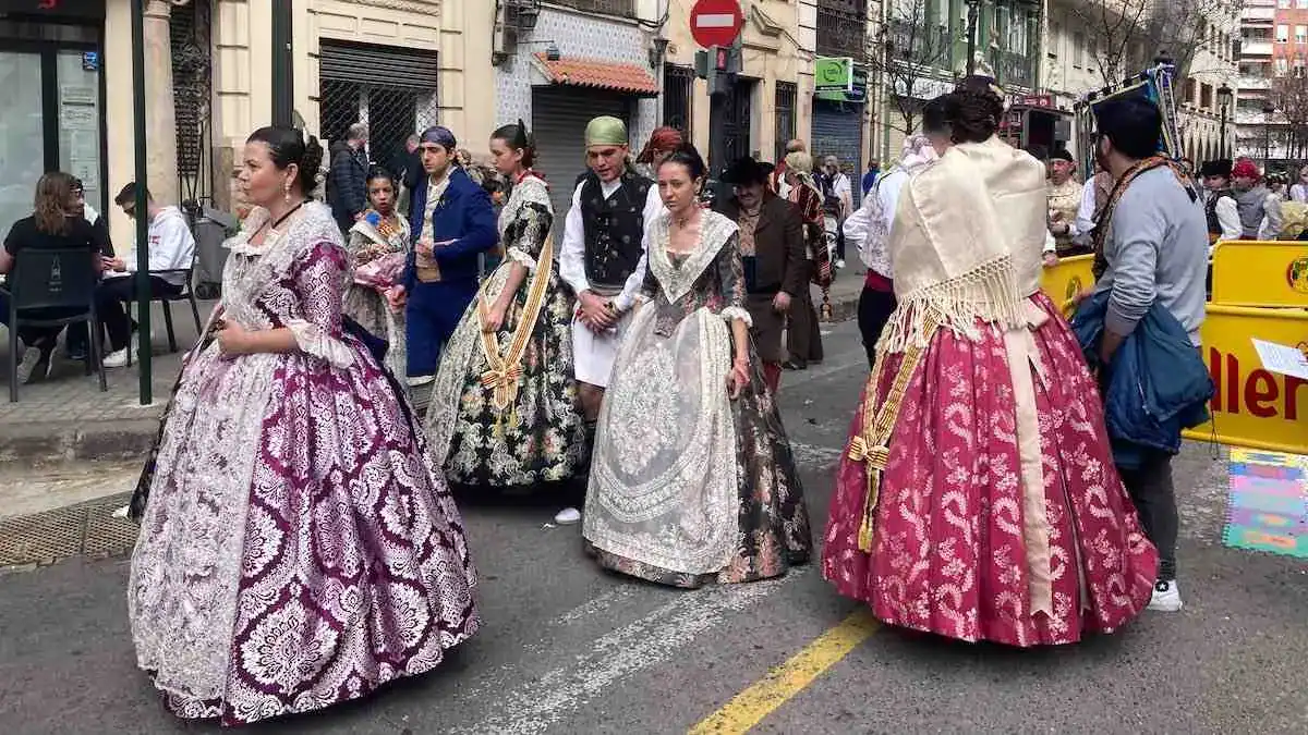 Women in elaborate traditional dress walk down a street in Valencia during the Fallas festival.