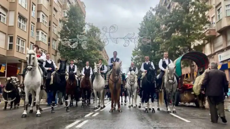 A line of men on horseback participating in a local festival along a street in Valencia
