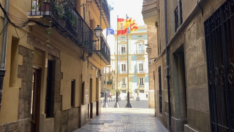 Flags of Spain and Valencia flutter at Plaza Manises at the end of a small street in El Carmen.
