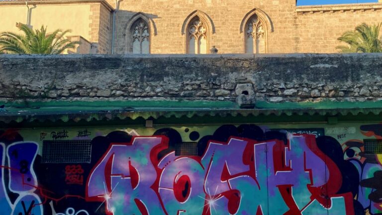 Colorful graffiti in the Turia Park beneath historic stone buildings in Valencia