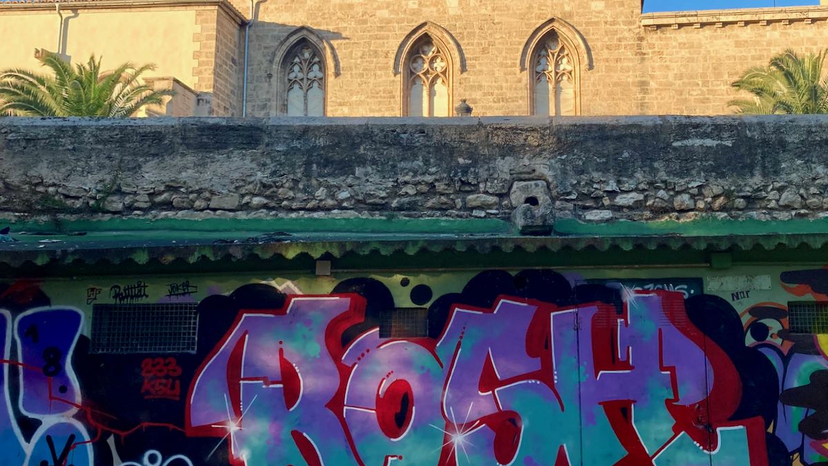 Colorful graffiti in the Turia Park beneath historic stone buildings in Valencia