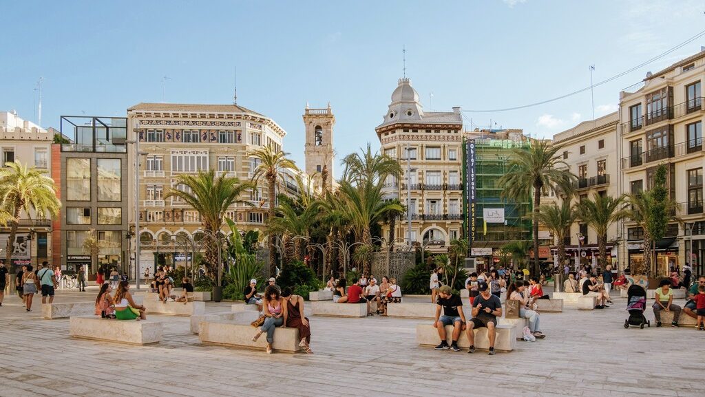 People sitting at stone benches at a plaza in Valencia, Spain