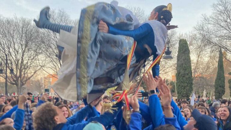 A woman in traditional Valencian dress is tossed in the air by partying residents during the Fallas festival of La Crida