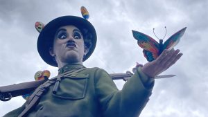 Paper mache figure of Charlie Chaplin holding a colorful butterfly