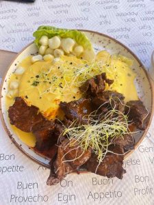 A plate of potatoes in yellow chilli sauce and with beef hearts, a specialty of Peruvian food