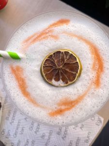 Foamy top of drink with preserved lime, known as pisco sour.