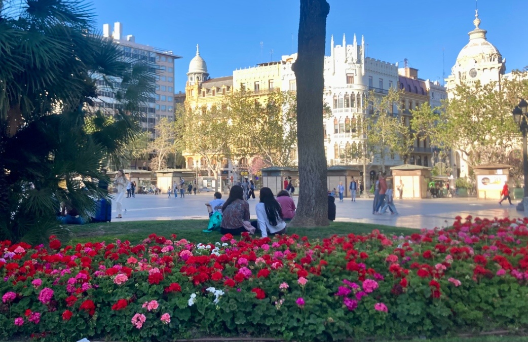 A couple sits among red flowers at the central plaza in Valencia, Spain