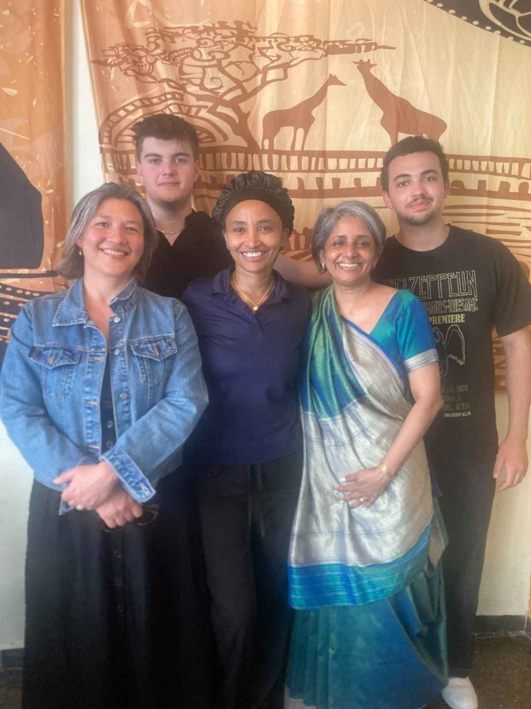2 customers gathered with a chef and kitchen staff smiling at the camera.