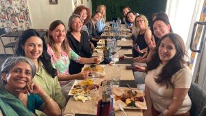 A group of people gathering for a meal looking at the camera and smiling.