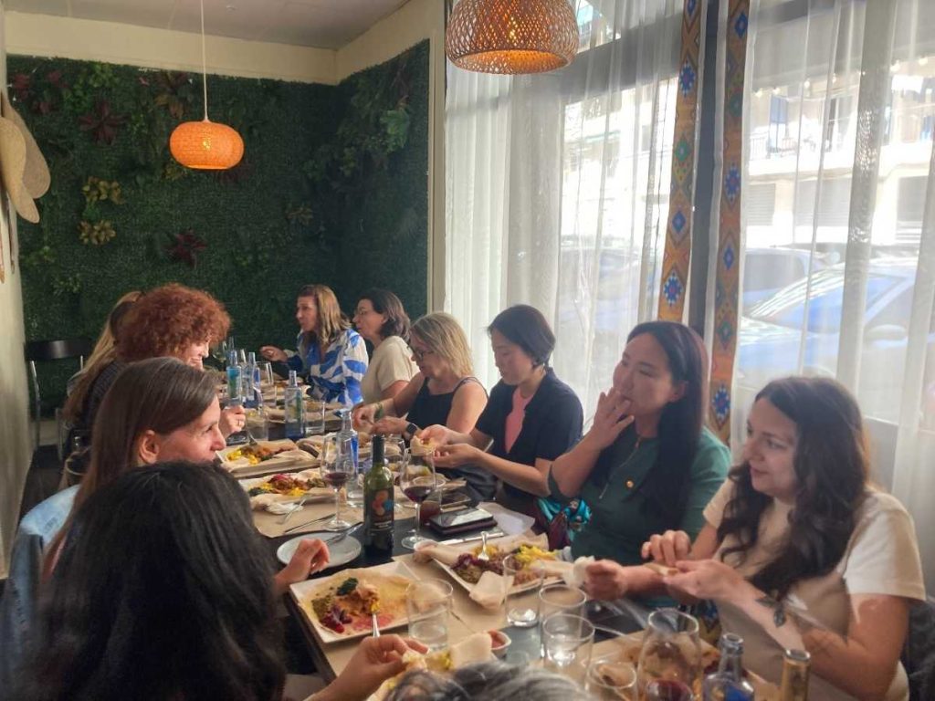 A group of people eating around a long table sharing lunch together.