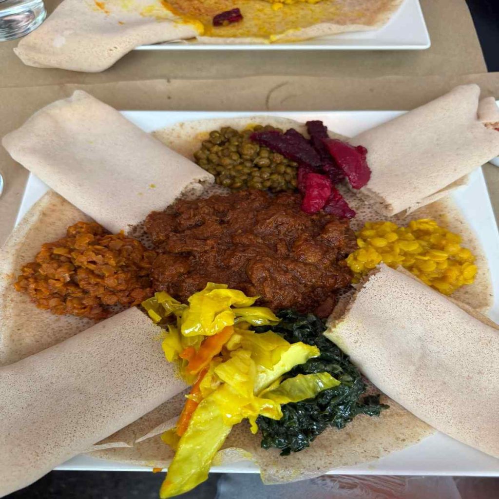 A plate of Eritrean and Ethiopian food of stewed lentils and vegetables with steamed sourdough flatbread.