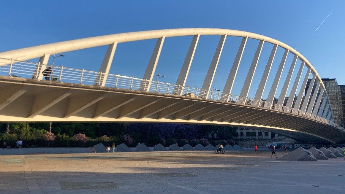 A view of the modern steel arc of the bridge Pont de l'Exposicio crossing over the Turia park on a sunny day with blue skies