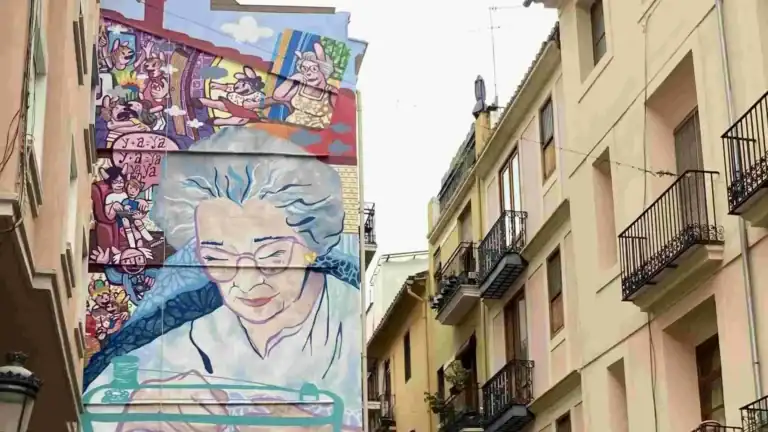 Large mural of a grandmother sewing on the side of a building in the El Carmen neighborhood of Valencia