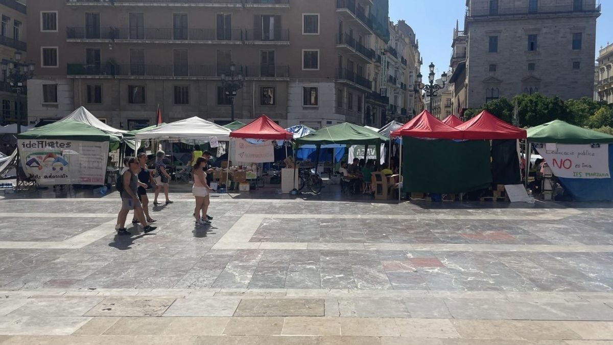 Pedestrians walk past a row of tents erected in Plaza de la Virgen as part of a teachers strike to improve working conditions in Valencia, Spain.