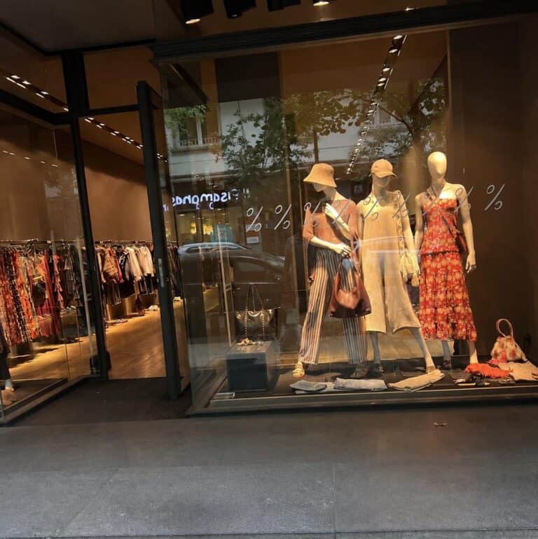 Fashion mannequins in a store window with summer outfits and accessories.