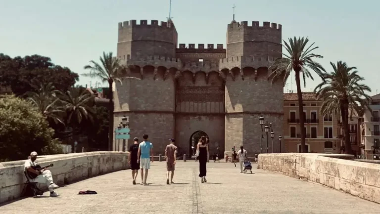 Valencia's iconic Serrano Towers in the summer with a guitarist busking at the bridge