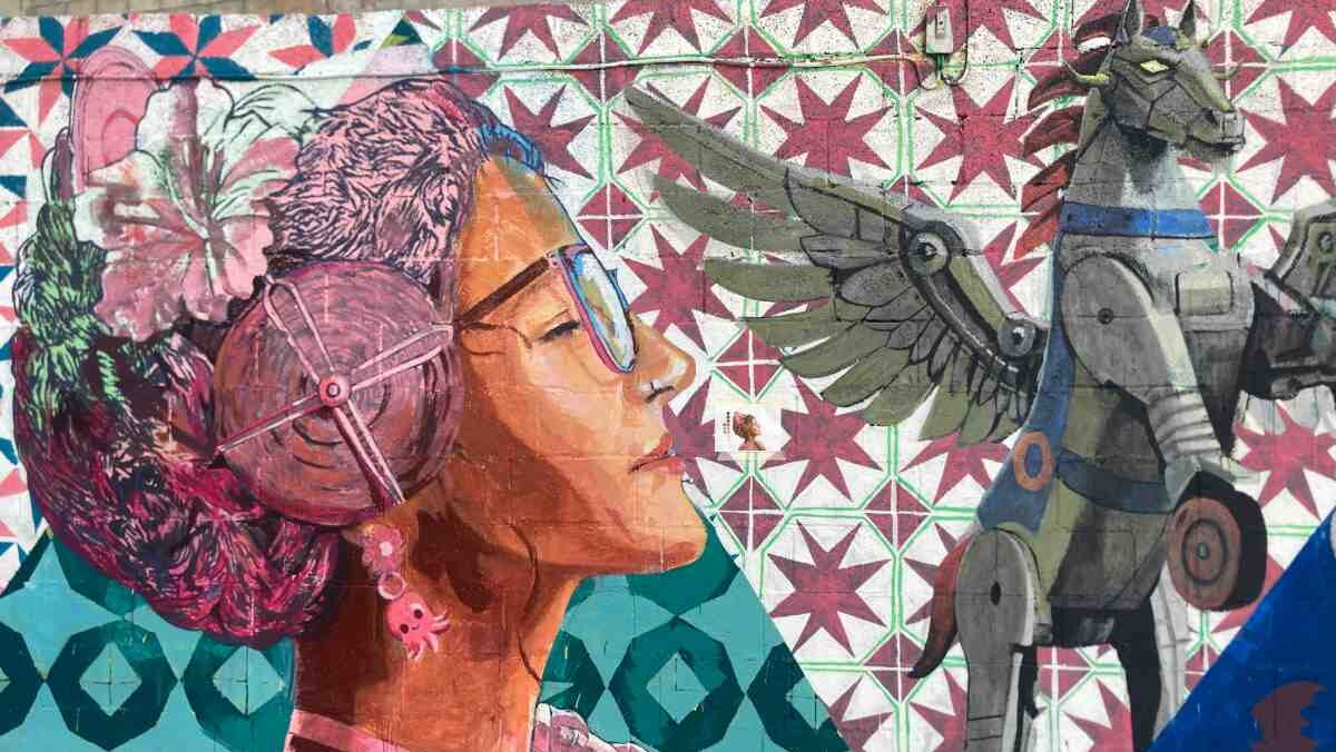Colorful street art in the El Carmen neighborhood of Valencia depicting a traditionally dressed Fallera with glasses looking up at a winged horse