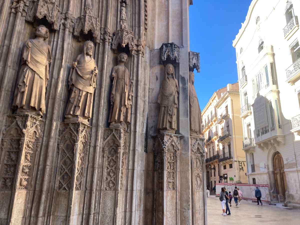 Stone statues carved into the arches of Valencia's Cathedral entrance facing the street.