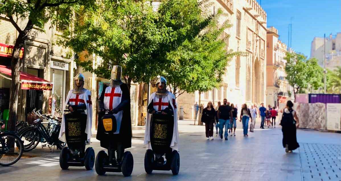 Fancy dress medieval knights riding on Segways in fron tof Valencia's historic Llonja de la Seda